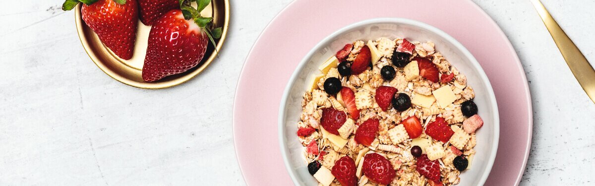 Strawberry Cheesecake Müsli in einer Schale mit frischen Erdbeeren.